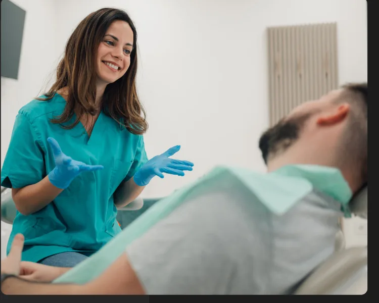 Dentista sorrindo durante atendimento ao paciente